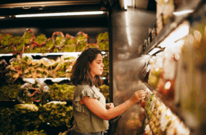Jovem consumidora avaliando frutas frescas no supermercado .