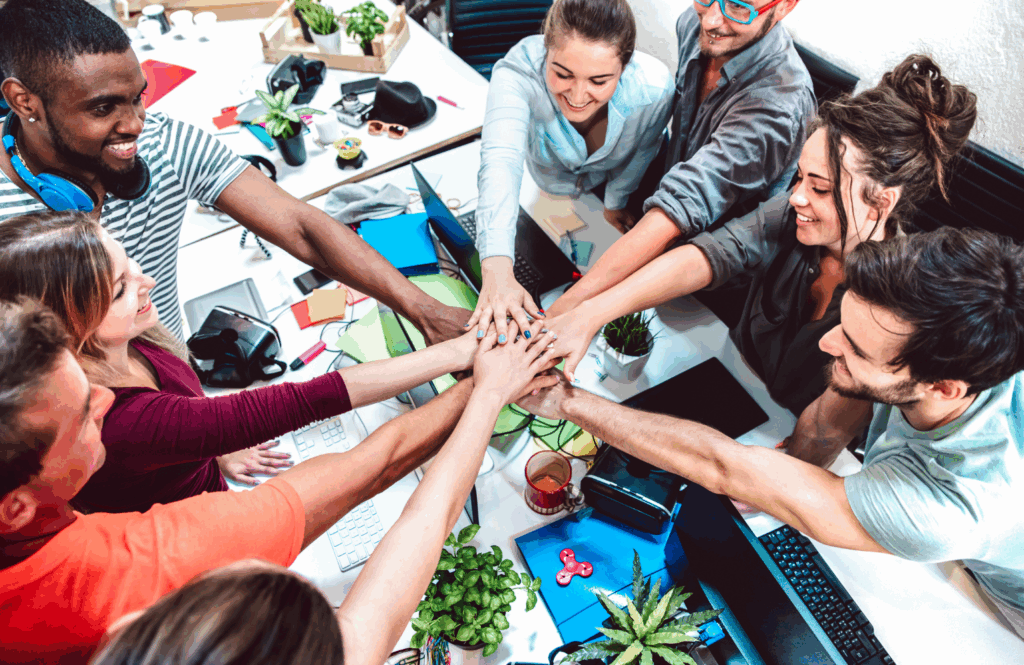 Equipe diversa reunida com as mãos unidas simbolizando colaboração e apoio ao canal de denúncia.