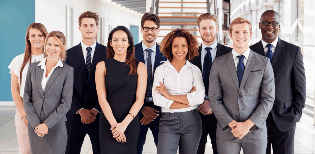 Grupo de executivos em trajes formais posando em ambiente corporativo.
