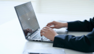 Mãos digitando em um laptop, ilustrando a gestão de dados de forma segura com um Canal LGPD eficiente.