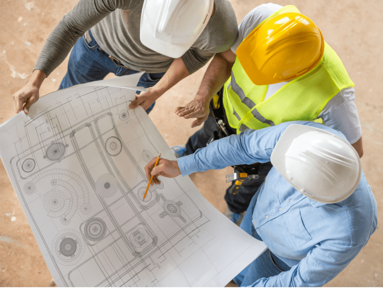 Três profissionais da construção civil, com capacetes de segurança, revisam uma planta baixa em obra — destaque para a importância de um canal de denúncias na construção civil para garantir segurança e conformidade.