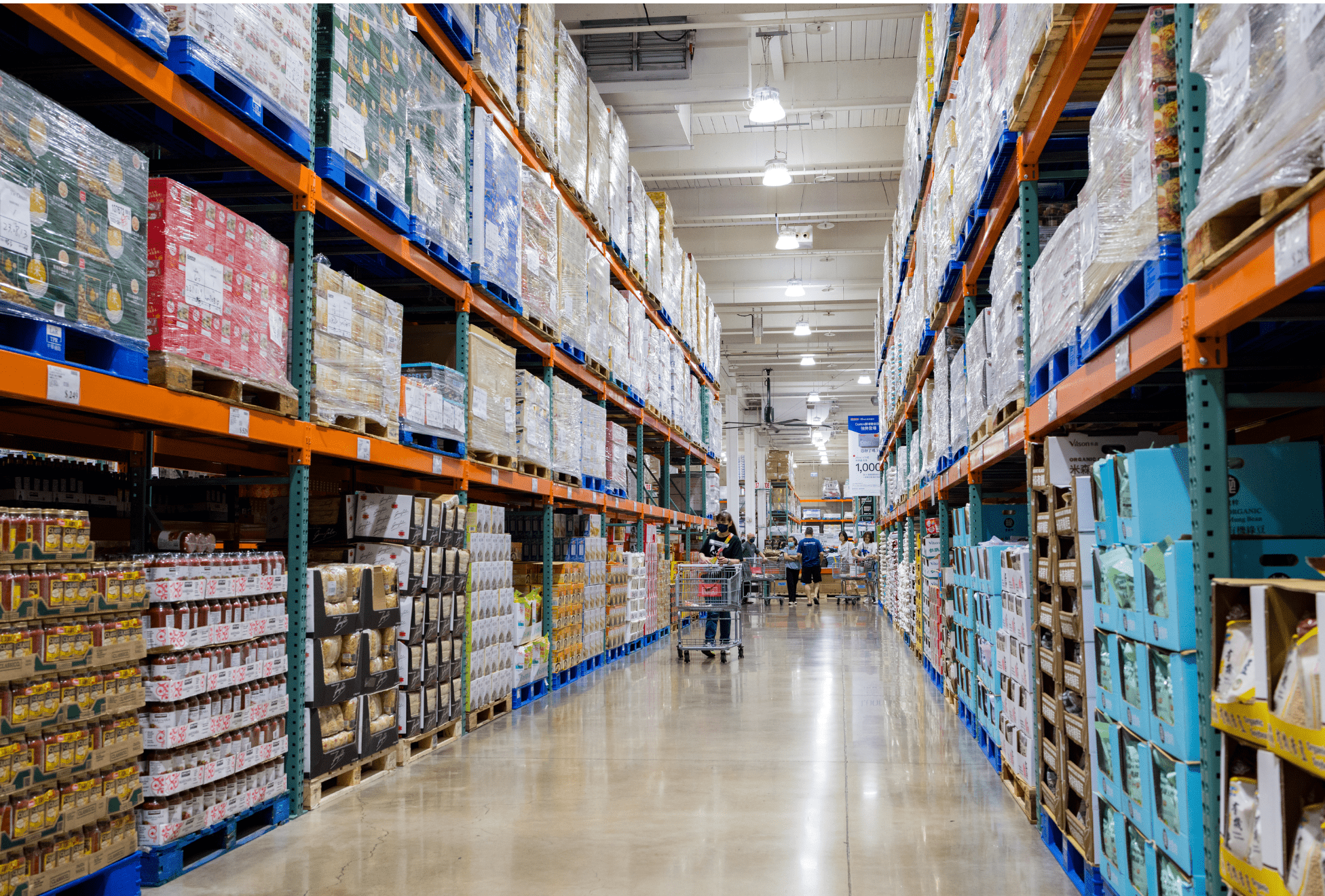 Corredor de um grande centro de distribuição com produtos empilhados em paletes, ilustrando a importância do Canal de denúncias no varejo e atacado para garantir transparência e ética nas operações.