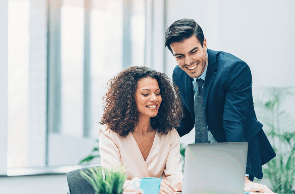 Dois profissionais trabalhando juntos em frente a um laptop em um escritório moderno, representando práticas de LGPD para empresas.
