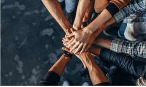 Mãos de diferentes pessoas unidas em sinal de cooperação e confiança, representando valores coletivos e o papel do canal de denúncias em cooperativas para fortalecer a integridade organizacional.