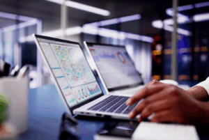 Profissional utilizando laptop com dashboards analíticos em um canal de denúncias mercado financeiro