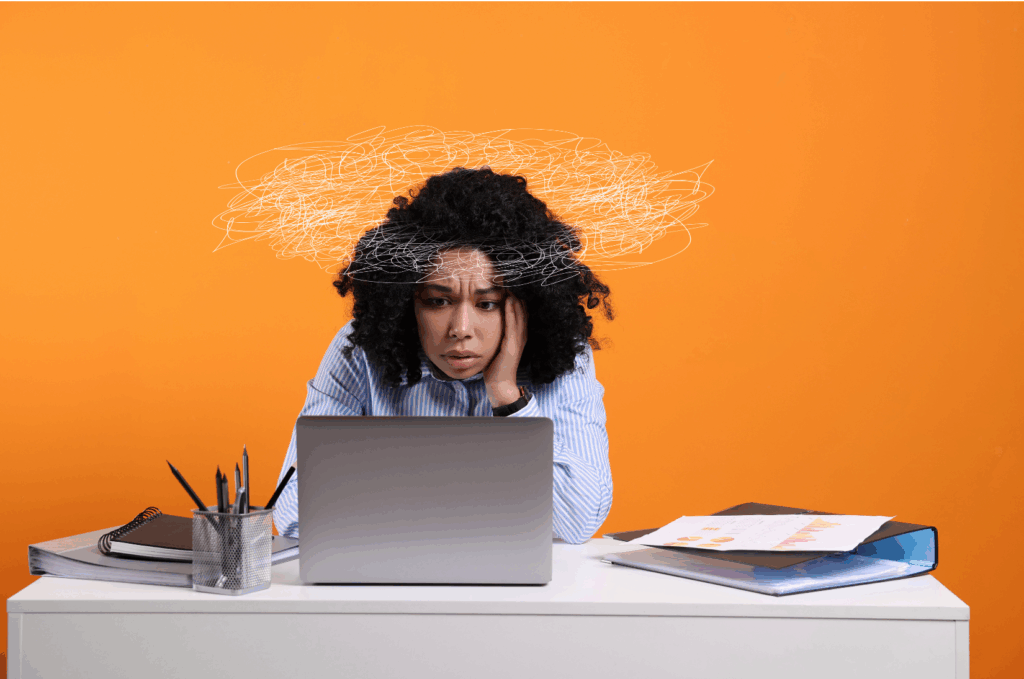 Profissional diante de um notebook com expressão de cansaço e confusão mental, representando sintomas de esgotamento ocupacional e a relevância de um canal de denúncias burnout assédio NR-1.